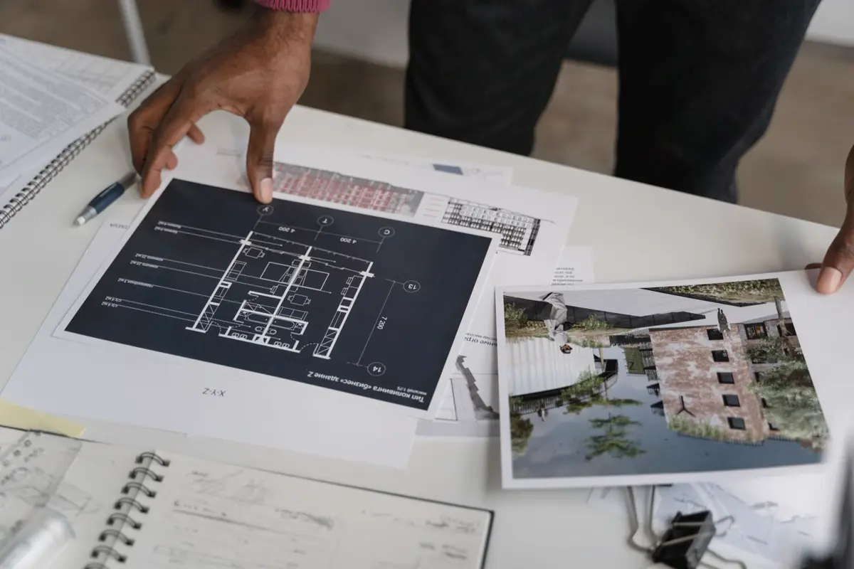 Planos y fotografías de un proyecto sobre una mesa de trabajo